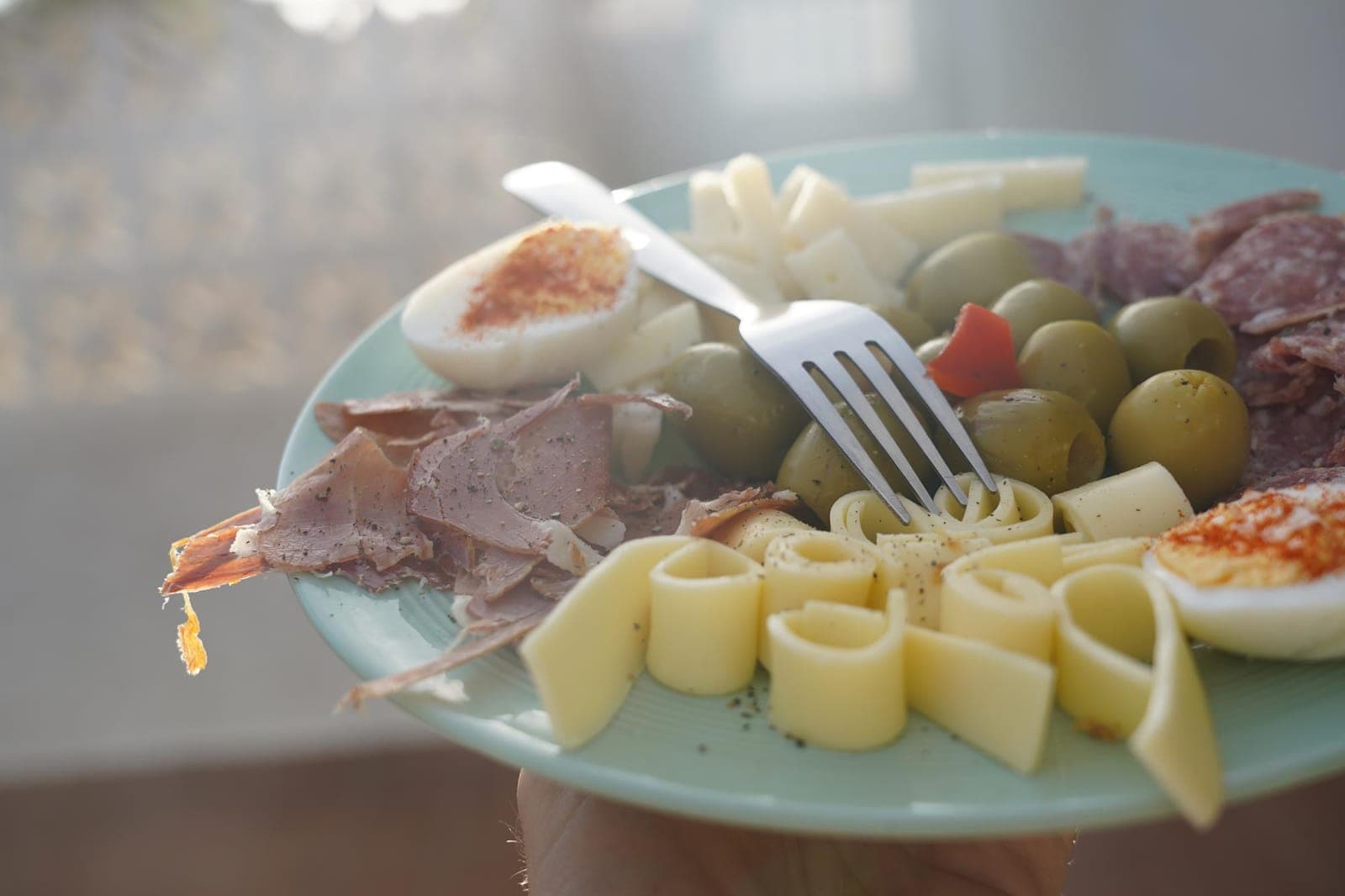 Teller mit Käse-, Wurst- und Schinkenauswahl, Oliven und Ei